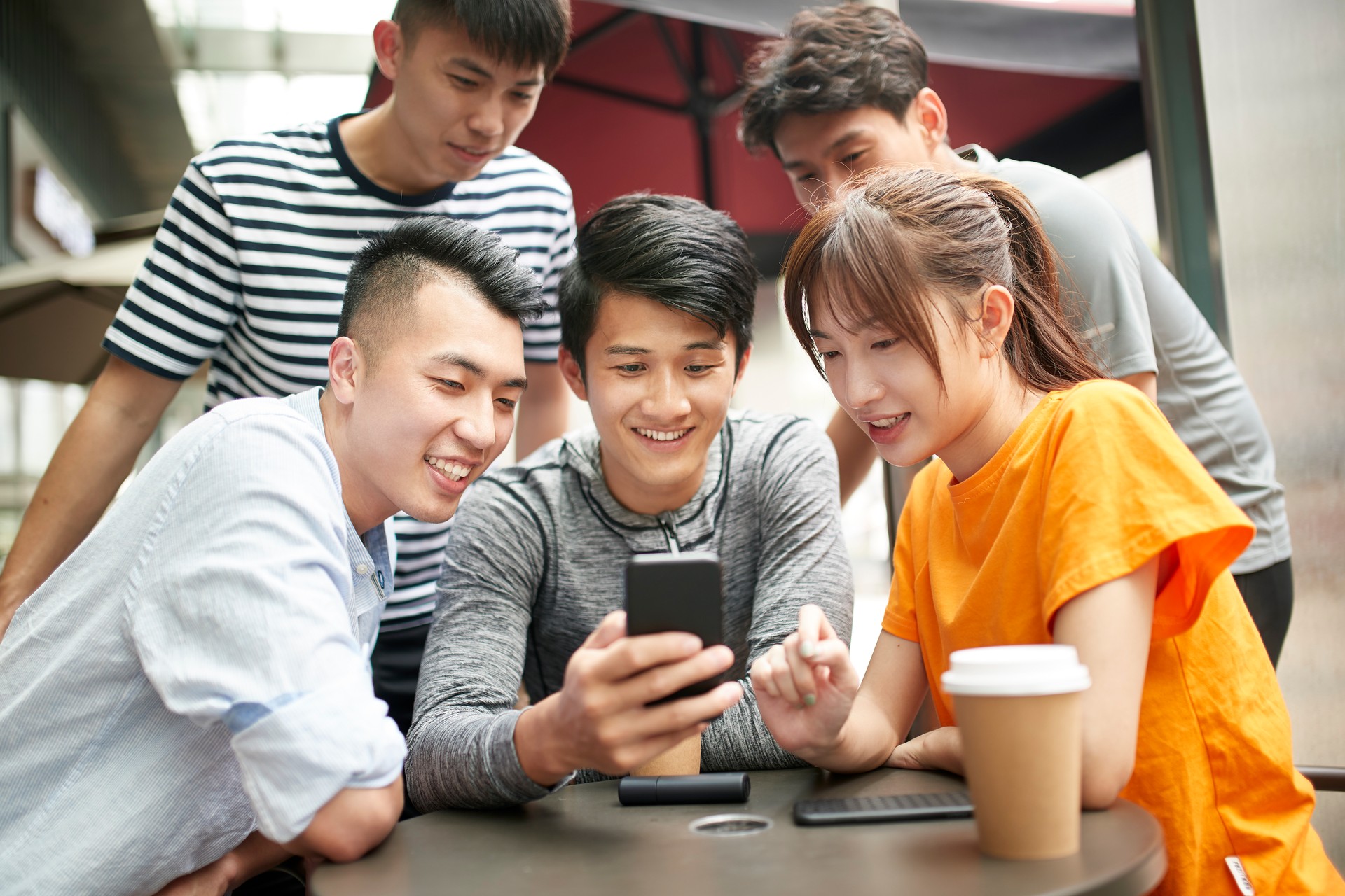 group of five asian young adults relaxing in outdoor cafe