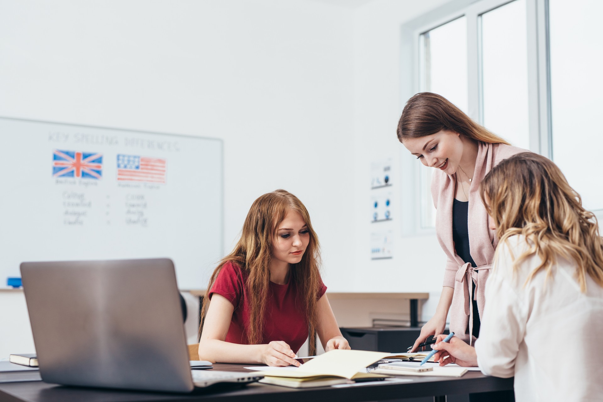 Young woman teaching English to adult students at language school.